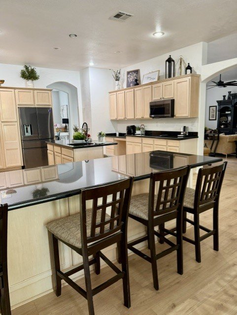 Open-concept kitchen with light wood cabinetry, dark granite counters, and a bar-height island.