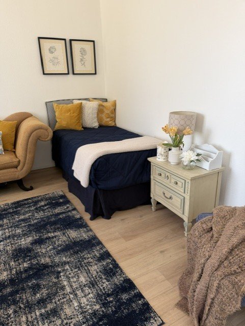 A private bedroom at Wisteria RALF with navy and gold linens beside a cream nightstand.